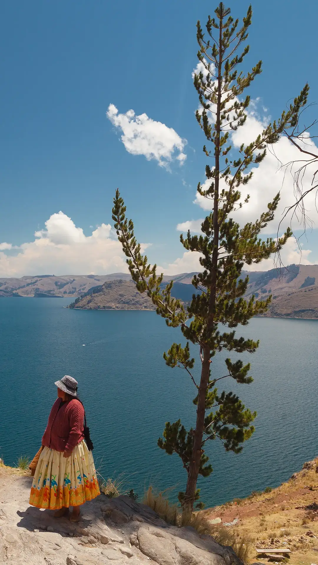 Two women in traditional Bolivian clothes standing on the rock close to the Titicaca Lake.