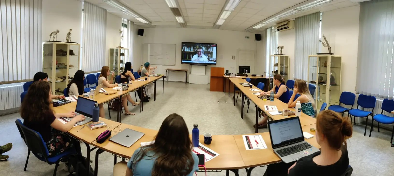 students in a room looking at lecturer on screen